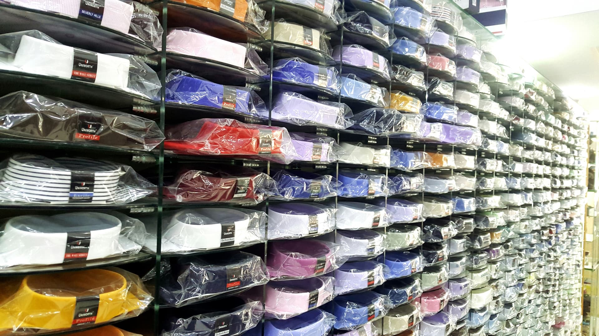 Neatly folded dress shirts wrapped in clear protective plastic packaging on white surface