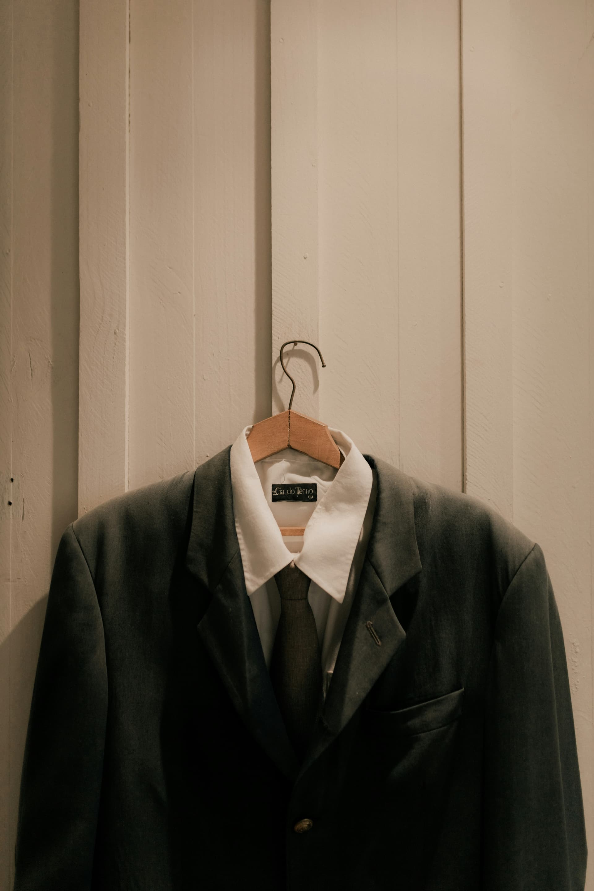 Wrinkled white business shirt with visible creases on wooden hanger